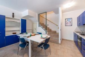 a kitchen with blue cabinets and a white table and chairs at Nice apartment Le Vele Garda Lake in Toscolano Maderno