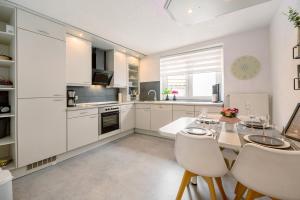 a kitchen with white cabinets and a table and chairs at Ferienwohnung My Suite Home in Illingen