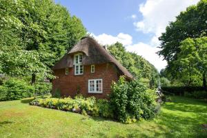 a small brick house with a thatched roof at Ferienhaus Reetkate Breklum in Breklum
