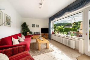 a living room with a red couch and a large window at Ferienwohnung Tibo in Wimbach
