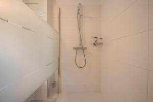 a white bathroom with a shower with a hose at Ferienhaus Spaden in Spaden +20 photos