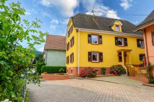 a yellow house with black windows and flowers at Villa Balboa in Sondernach