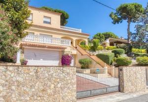 a house with a stone wall and a fence at Costacabana - Villa Paris in Lloret de Mar