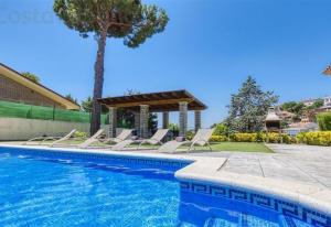 a pool with chairs and a gazebo at Costacabana - Villa Paris in Lloret de Mar