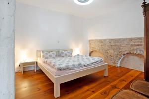 a white bed in a room with a brick wall at Alte Seifensiederei 3 in Stralsund