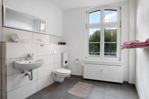 a white bathroom with a toilet and a sink at Alte Seifensiederei 3 in Stralsund +15 photos