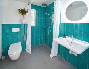 a blue tiled bathroom with a toilet and a sink at Große Atelierwohnung Barrierefrei in Meezen