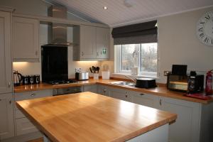 a kitchen with a wooden counter top and a clock on the wall at Golden Cross Holiday Park in Hailsham