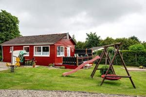 a playground in front of a small red house at Ferienhaus Landhaus Loose in Schashagen
