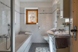 a bathroom with a tub and a sink and a toilet at Malsötscherhof Apt A in Villandro +26 photos