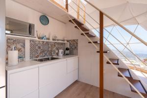 a kitchen with white cabinets and a spiral staircase at Dome on the hill with Jacuzzi in Castellammare del Golfo +20 photos