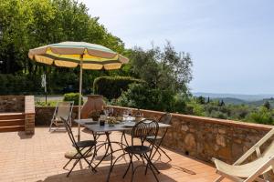 a table with chairs and an umbrella on a patio at Podere San Bartolo- Fienile in Barberino di Val dʼElsa