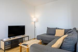 a living room with a couch and a flat screen tv at Le Gite De Luca in Husseren-les-Châteaux
