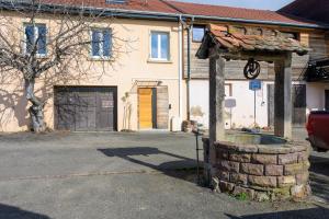 a building with a stone fountain in front of a house at Le Gite De Luca in Husseren-les-Châteaux