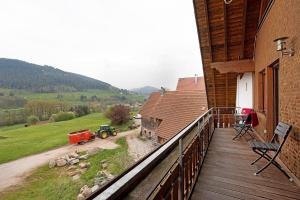 a balcony of a house with a tractor on a field at Wohnung Kuhblick in Baiersbronn
