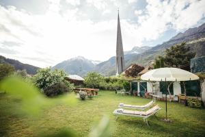 a garden with a bench and a church with a steeple at Freienfeldhof Golden in Lagundo