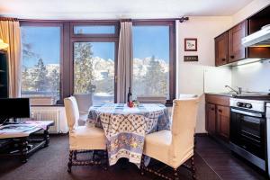 a kitchen with a table and chairs and a table and some windows at 3Tre Patascoss-Madonna di Campiglio in Madonna di Campiglio