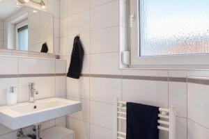 a white bathroom with a sink and a mirror at Haus Lerchenweg B in Bad Wildungen +21 photos