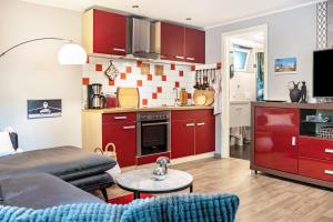 a living room with red cabinets and a kitchen at Bungalow Passat - Bgl 5 in Dranske +13 photos