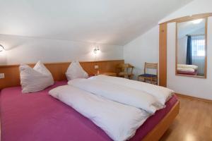 a bedroom with a large bed with white sheets and a mirror at Haus Peer Burgeis in Malles Venosta