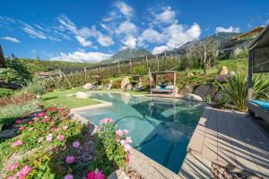 a swimming pool in a garden with flowers at Feldhof Apartment Apfeloase in Caines