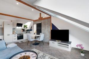 a living room with a tv and a kitchen at Le Quartier Blackforest-Straßburg in Willstätt