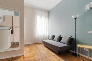 a living room with a couch and a mirror at GuestHost - Chic Flat Steps from Duomo in Milan