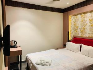 a bedroom with a bed with a red head board at Hotel The Palassio in Kānpur +4 photos