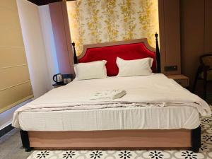 a bedroom with a bed with a red headboard at Hotel The Palassio in Kānpur
