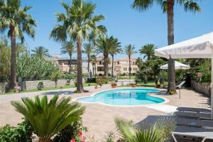a pool with palm trees and a building in the background at Erodios Villas 1 in Gerani