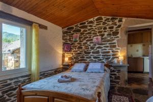 a bedroom with a bed in a stone wall at Les Gîtes du Mas Lachamp in Gravières