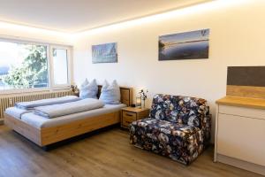 a bedroom with a bed and a chair at Höri-Nest Abendsonne-Appartement in Gaienhofen