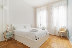 a white bedroom with a white bed and a chair at GuestHost - Chic Flat Steps from Duomo in Milan