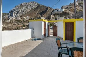 a patio with a table and chairs and a mountain at Villa Houvarda in Karpathos