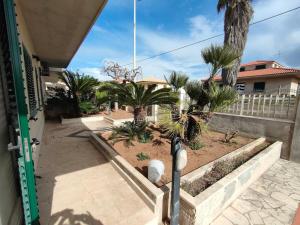 a courtyard with palm trees and a white fence at Villetta Roby in Marina di Modica