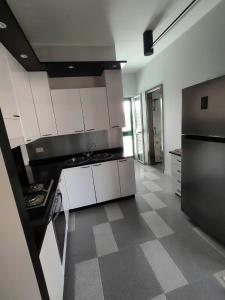 a kitchen with white cabinets and a black refrigerator at Villetta Roby in Marina di Modica