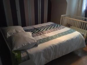 a unmade bed with a crib in a bedroom at Le Goéland in Sarzeau +6 photos