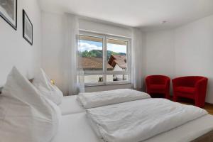 a white bedroom with two beds and a window at Ferienwohnung Rebenrain, 80qm in Steinach