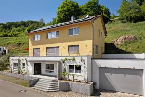 a large yellow house with a garage at Ferienwohnung Rebenrain, 80qm in Steinach