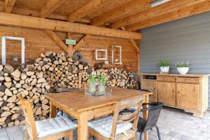 a wooden table and chairs on a patio with a pile of logs at Ferienwohnung Kleeblatt in Herbolzheim