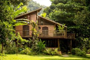 a wooden house with a deck in the woods at Paraty Paradiso in Parati-Mirim