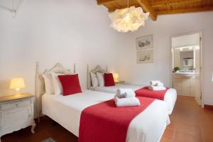 a bedroom with two beds with red and white sheets at Páteo da Várzea 3 in Colares