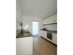 a kitchen with white cabinets and a wooden floor at Ferienhaus Melody in Ralswiek