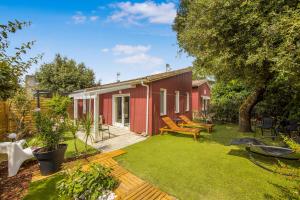 a garden with a red house with a lawn at Les chalets de Piqueyrot in Hourtin