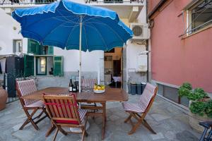 a wooden table with chairs and a blue umbrella at Appartamento Aurora in Corniglia +17 photos