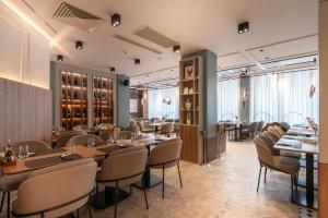 a restaurant with wooden tables and chairs and windows at Hotel Botika in Kraljevo