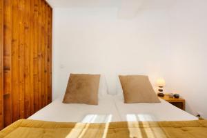 a bedroom with a white bed with a wooden headboard at Capelos in Funchal
