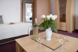a table with two wine glasses and a vase with white flowers at Ferienwohnung Laage in Laage