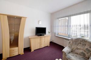 a living room with a tv and a chair and a window at Ferienwohnung Laage in Laage