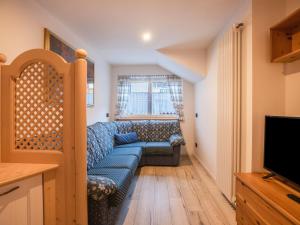 ein Wohnzimmer mit einer blauen Couch und einem Fernseher in der Unterkunft Chalet Osmar Appartamento 1 in Campitello di Fassa